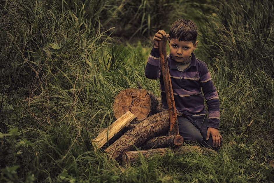 紫色条纹条纹男孩长袖衬衫在绿草地上拿木棒