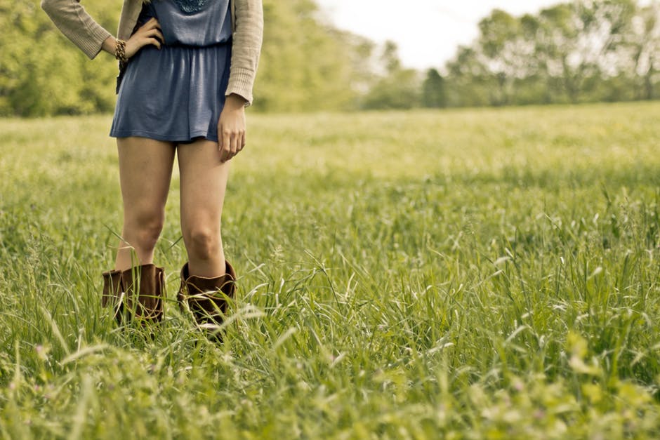 穿着棕色靴子的人站在绿色的草地上