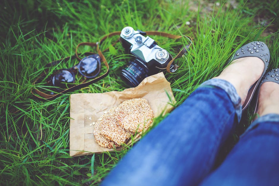 用饼干和照相机在草地上休息的女孩