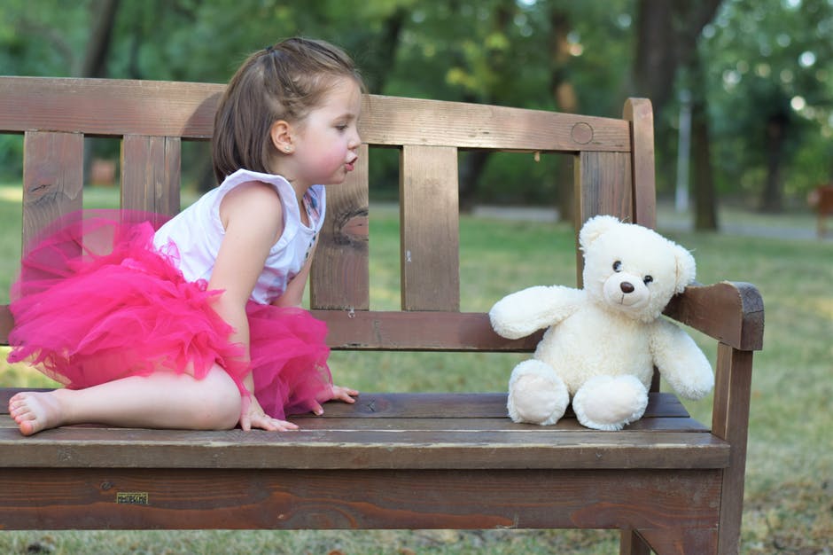 棕头发女孩穿着粉色兔兔裙贴近白色毛绒玩具