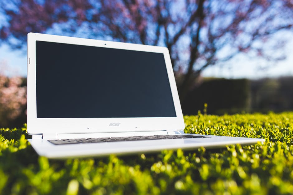 绿色草地上的白色笔记本电脑