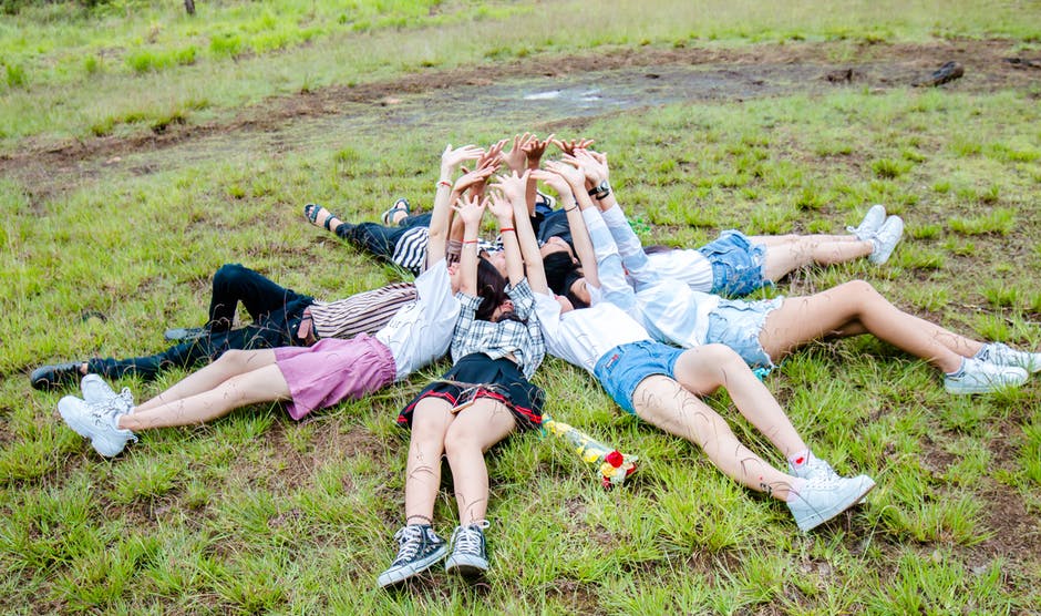 一群朋友在圈子里躺在草地上-手放在上面