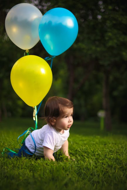 Baby Wearing White衬衫和三个气球绑在一起