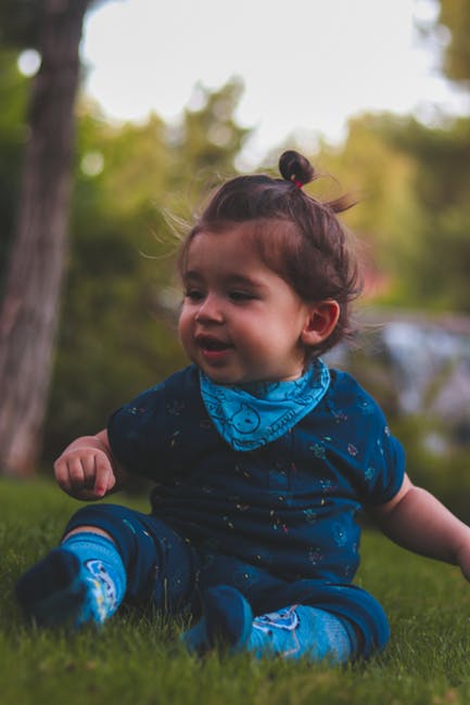 穿蓝色衣服的婴儿和坐在青草上的袜子