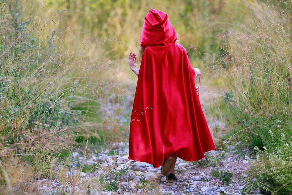 红帽女孩走在草地间的小路上