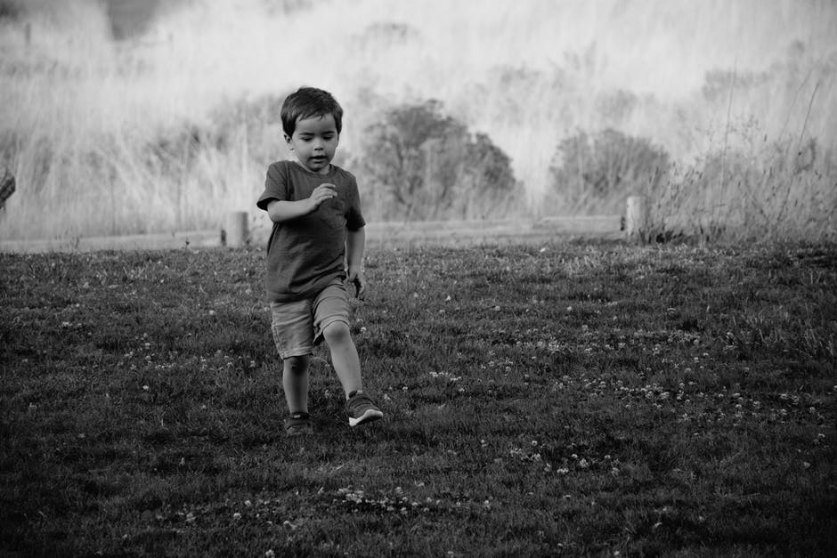 草地上儿童行走的灰度摄影
