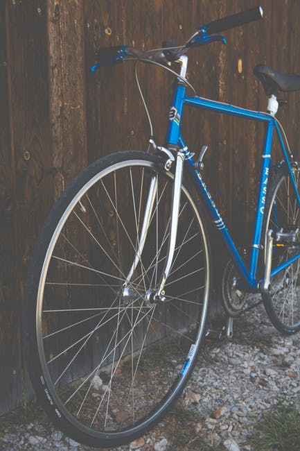 蓝色的城市自行车旁边的棕色木栅栏