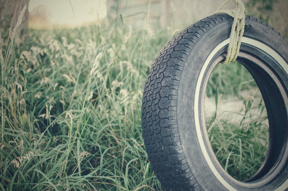 黑色轿车轮胎绑在Brown Rope附近的绿色植物白天