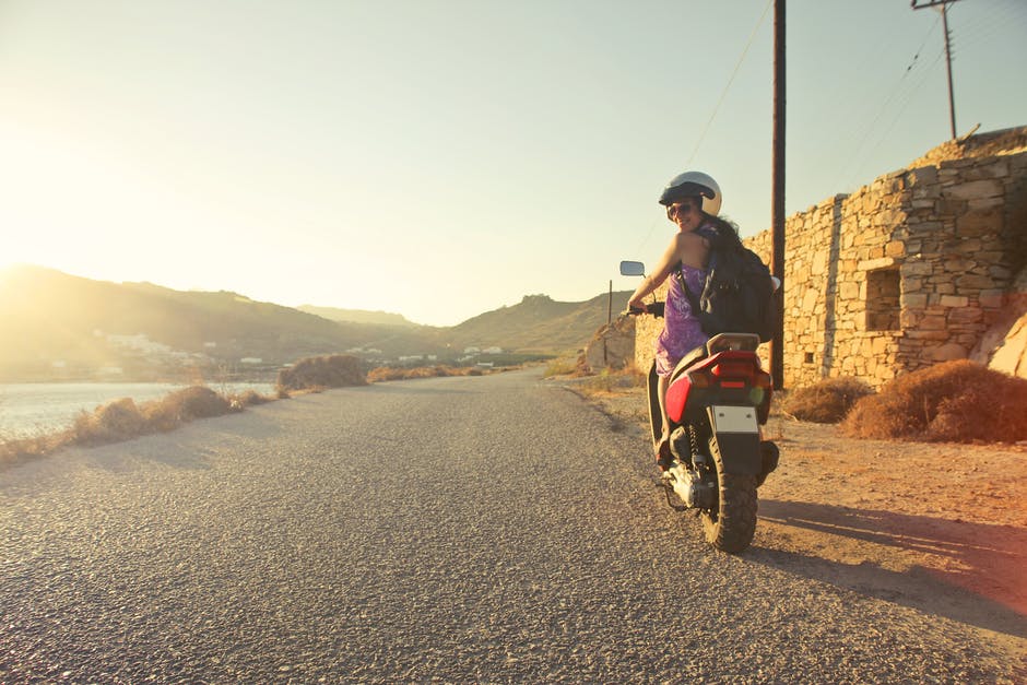 日出时妇女骑摩托车滑行于柏油路