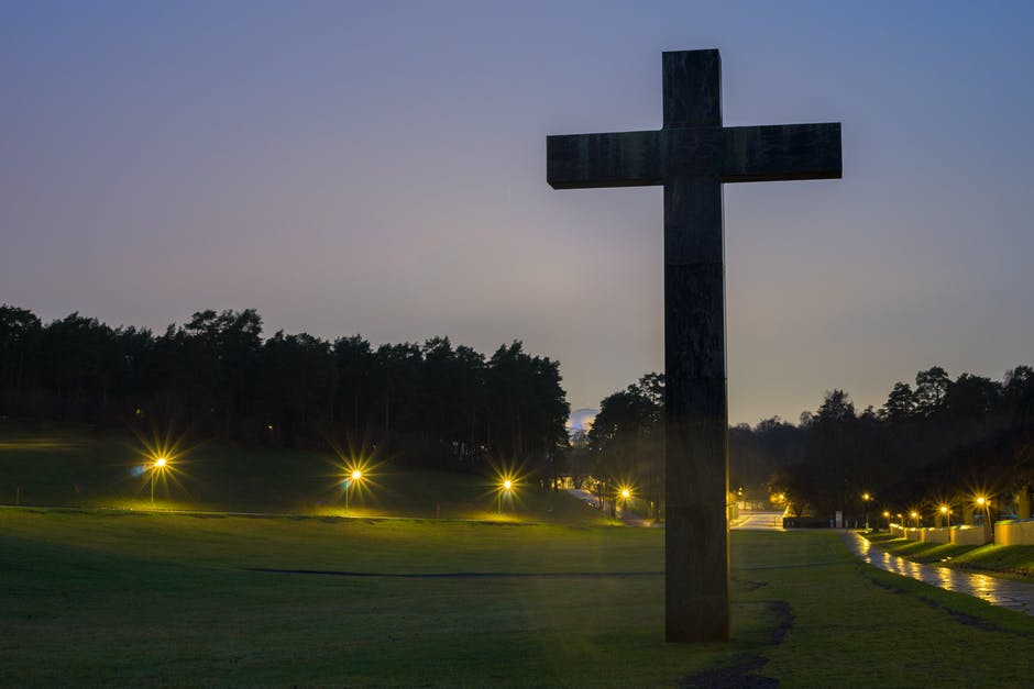 夜间开灯绿草地上的棕十字雕像