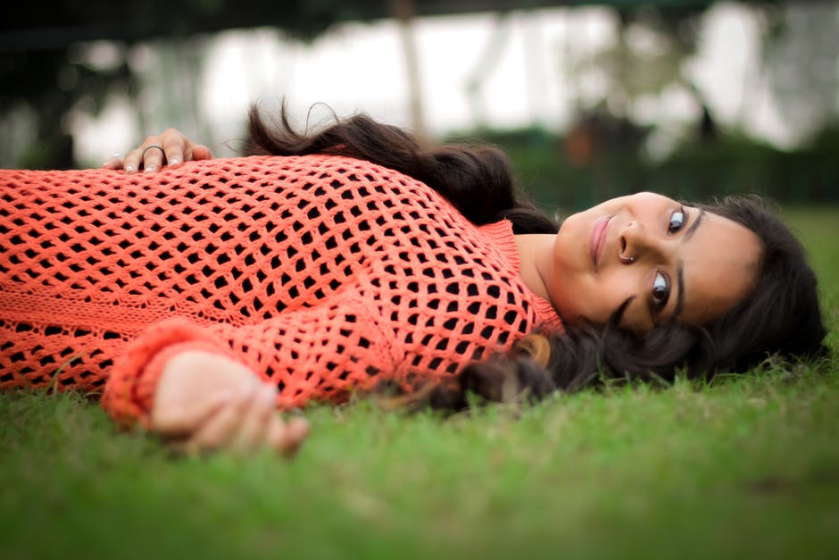 穿着橙色长袖衬衫躺在草坪上的照片女人