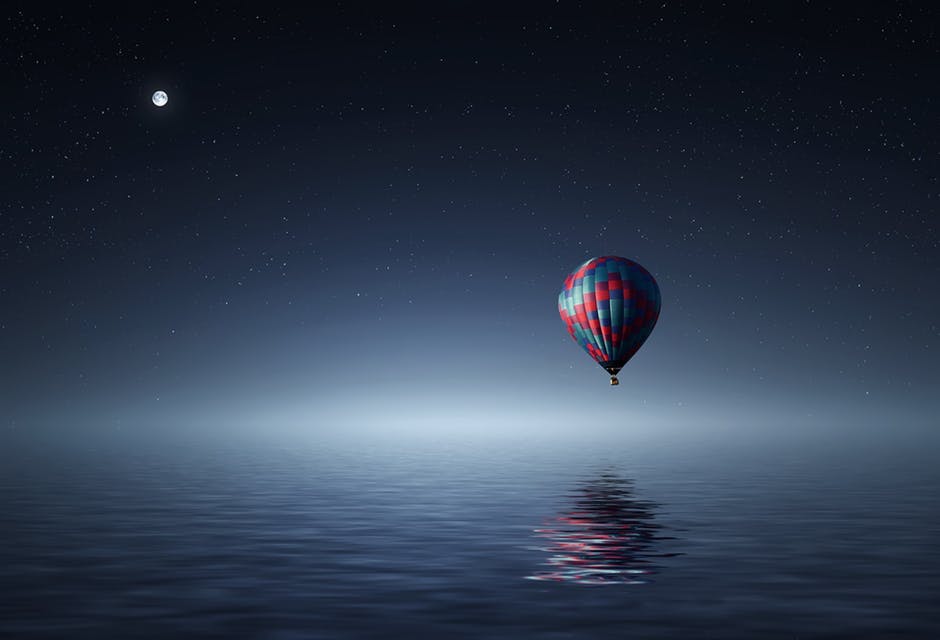 夜间红色和蓝色热气球漂浮在水体上