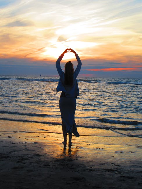 森塞特站在沙滩上怀着手臂做心脏标志的女人
