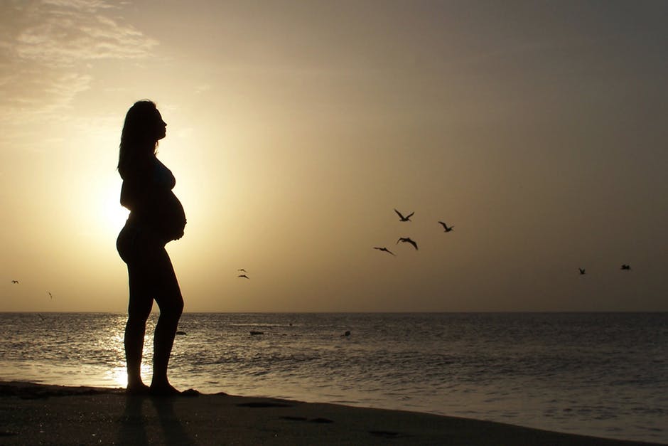 黄金时段孕妇站在海边的剪影
