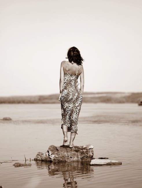 女人穿着豹纹裙站在水面上的石头上
