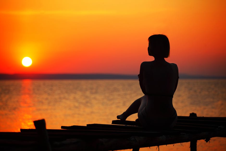 日落时坐在码头上的女子剪影