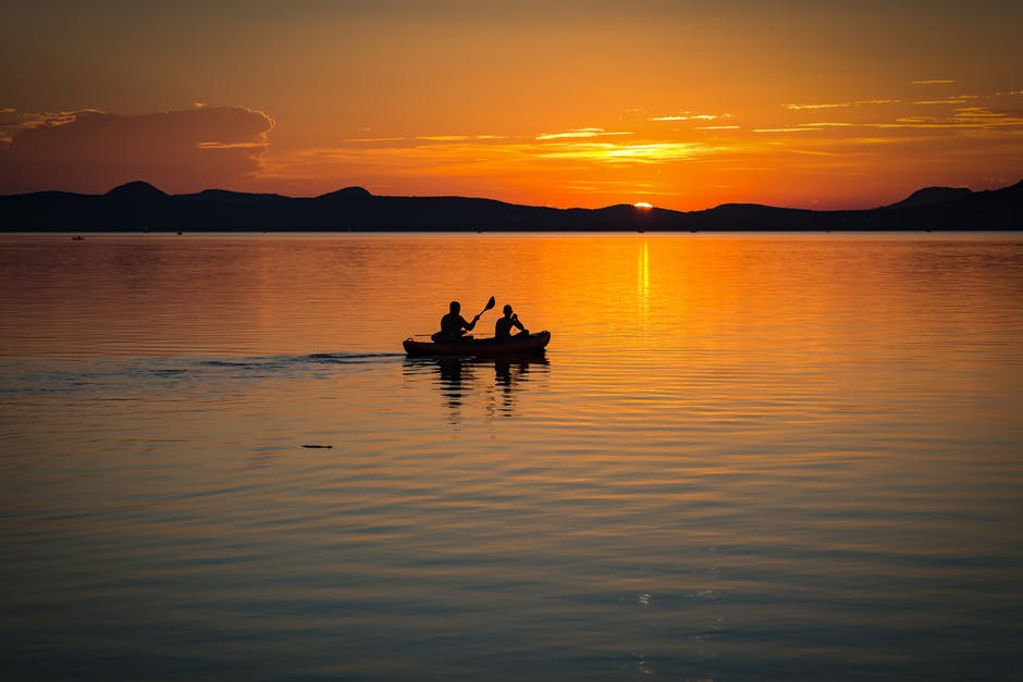 日落时船上2人在明水中航行