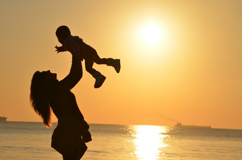日落时沙滩上抱着婴儿的女人