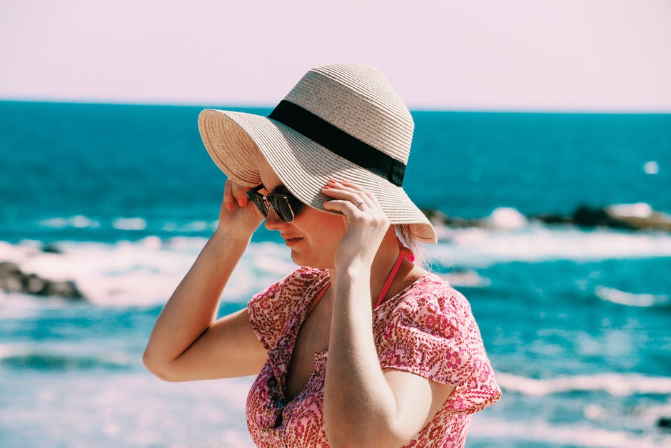 女人戴米色太阳帽白天站在水体后面的选择性焦点照片