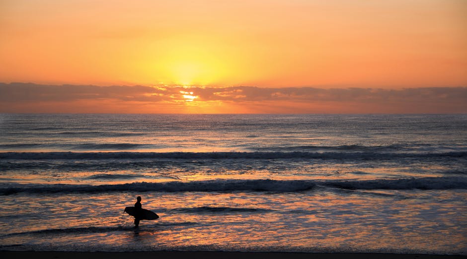 冲浪者在日落时摄影的照片