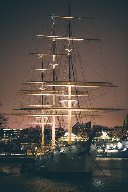 白色和棕色的船在夜间靠近建筑物