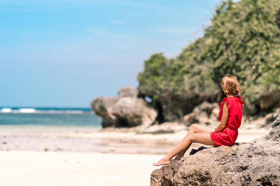 穿着红衣服的女人坐在棕色的岩石上