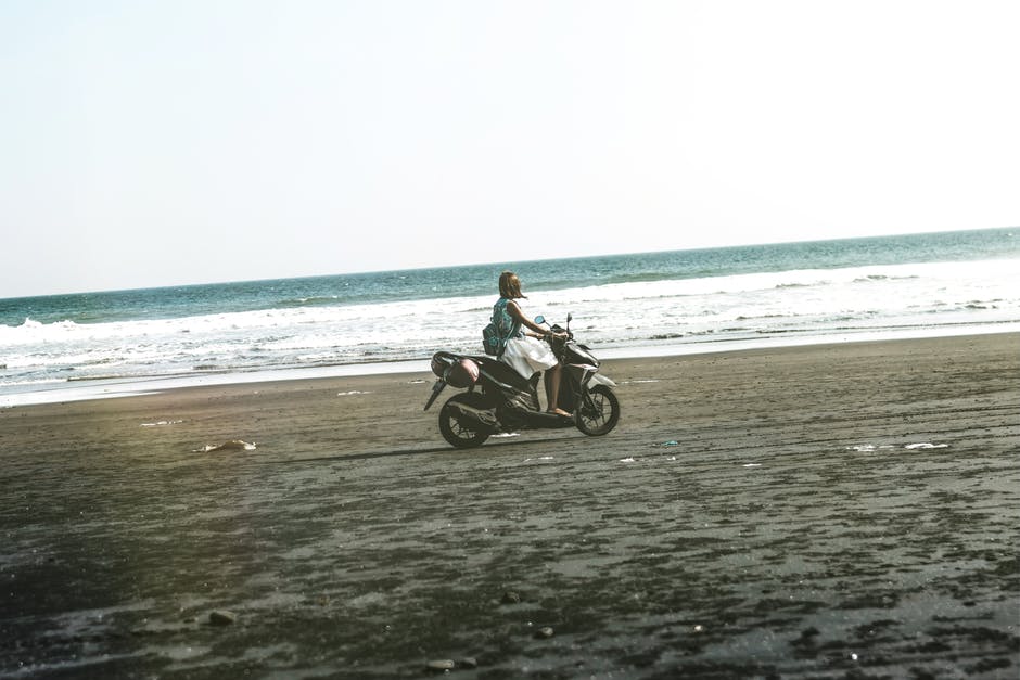 在Beach骑黑色和灰色摩托车的女人