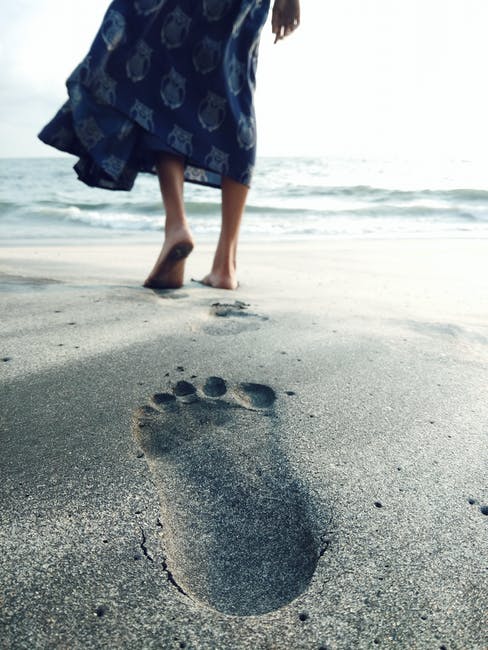 赤脚走在海边的女人的照片