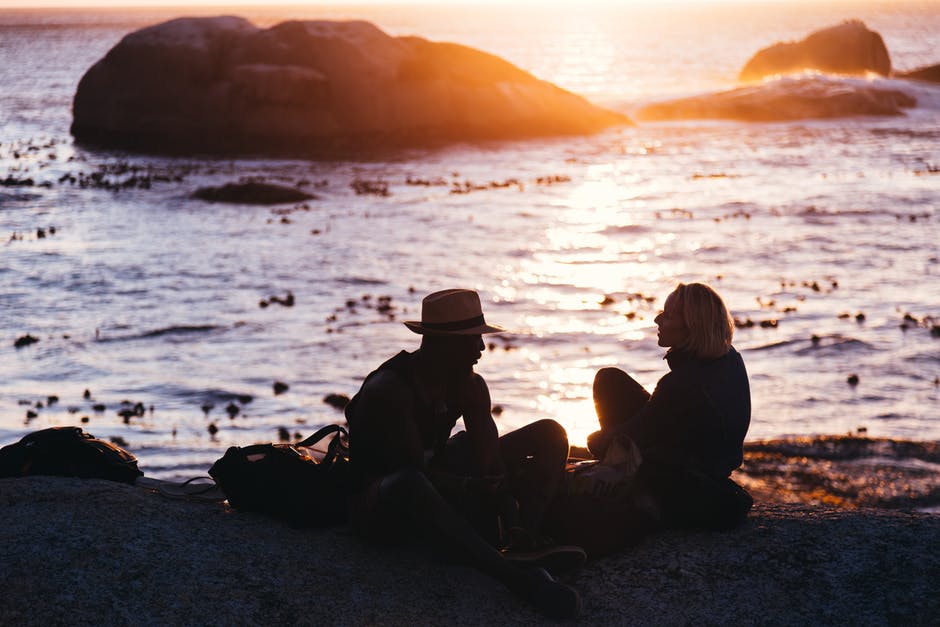 日落时坐在岸边的男人和女人
