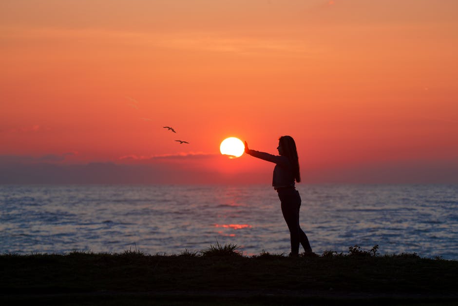 拂晓时站在海边的女人的照片