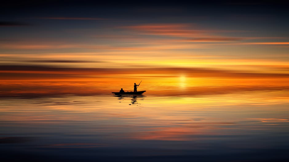 日落时划艇上的人的照片