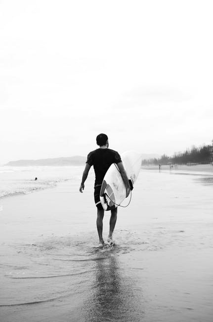 Man Carrying Surfboard的灰阶照片