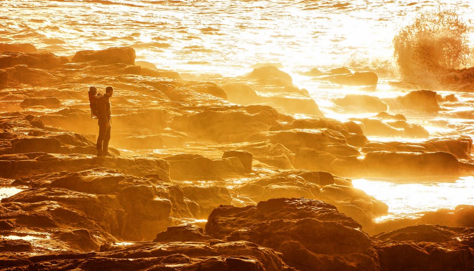 日落时站在岩石岸边的人