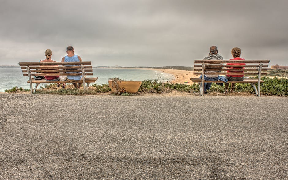 两对夫妇坐在海滩附近的长凳上