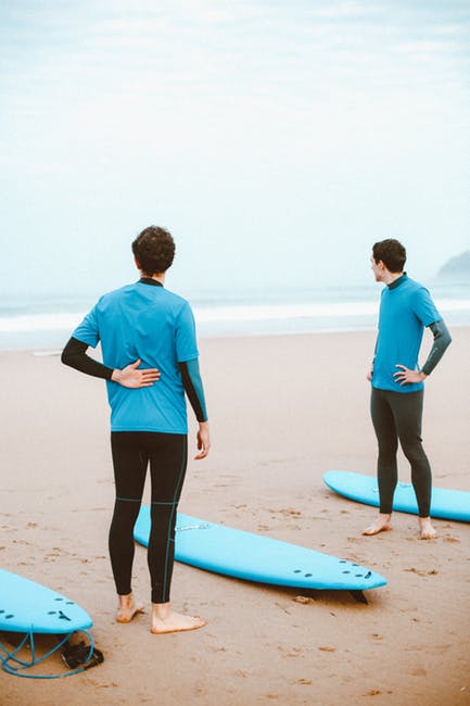两个人站在Beach冲浪板之间