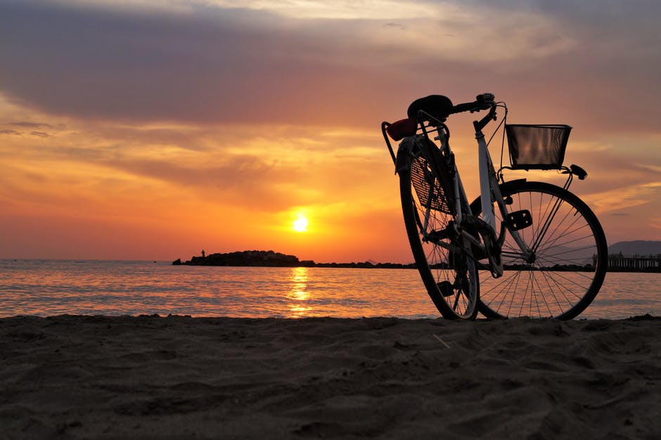 夕阳西下褐沙滩上的白色硬尾自行车