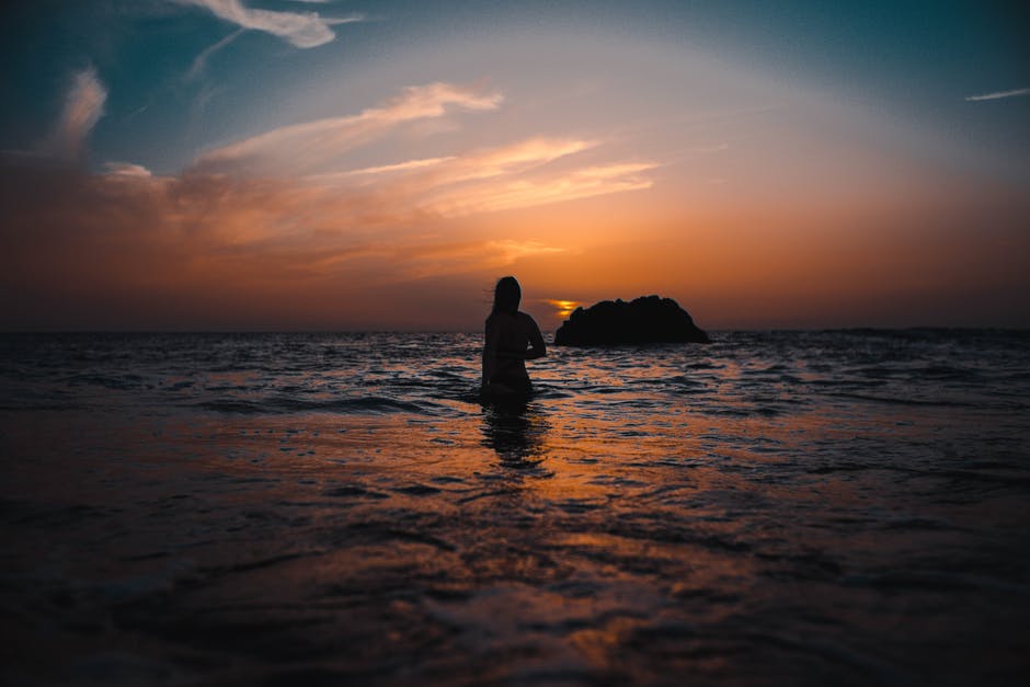 日落时海洋中的女人剪影