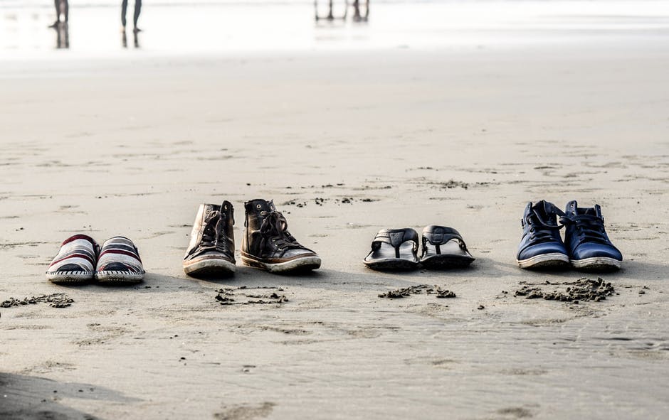 沙滩上各式各样的鞋的相片
