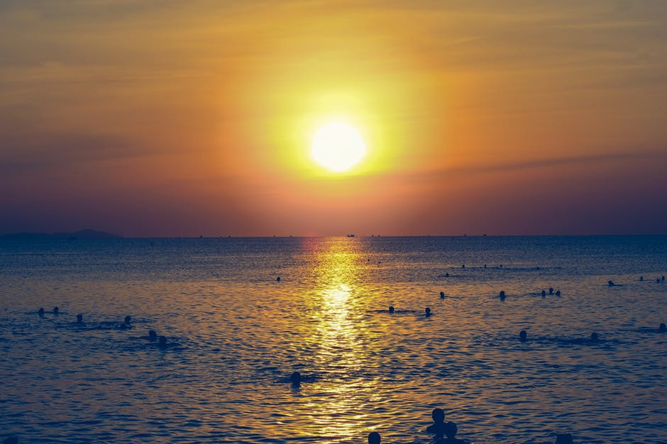 日落时在海洋中游泳的人影