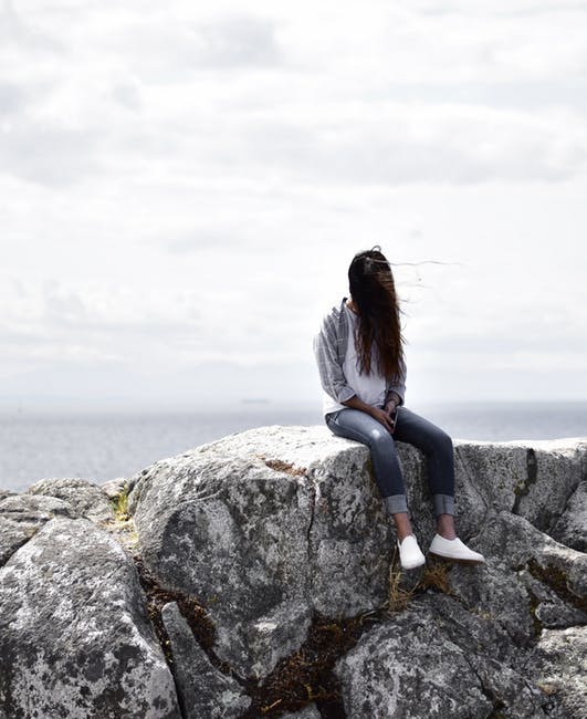 女人坐在灰色的岩石上