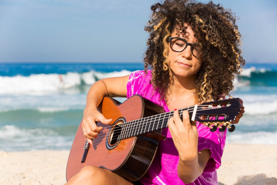 女主角身穿紫色衬衣-身着褐色古典吉他-白天坐在岸边-白天溅水