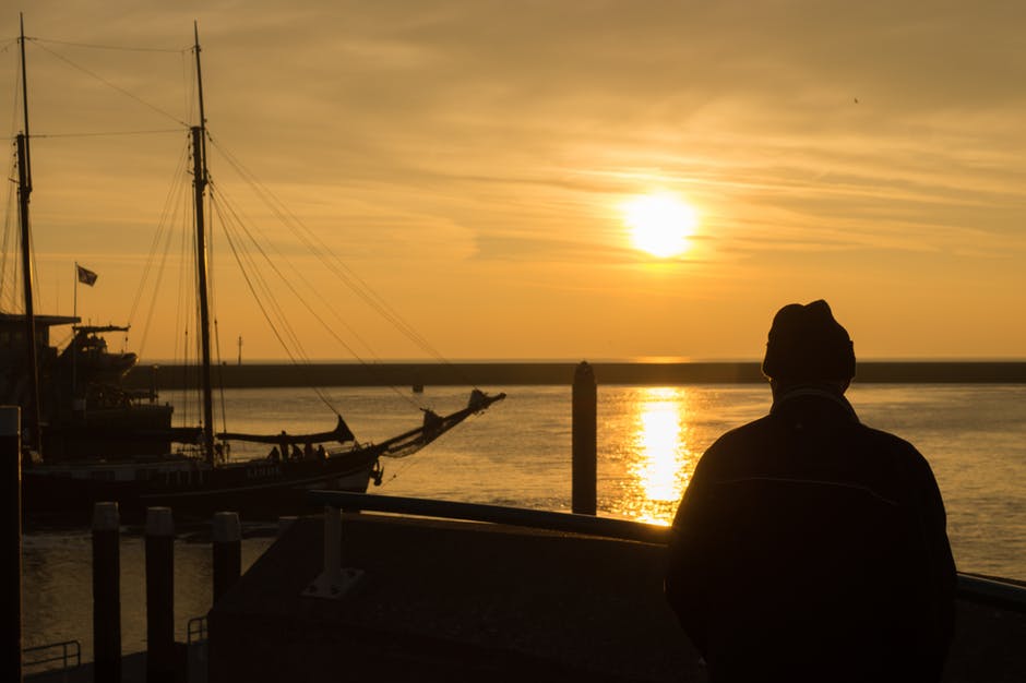日落时站在码头上的人